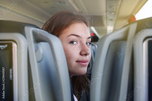 teenager girl is in the bus travelling sitting on the seat looking at the camera between the seats
