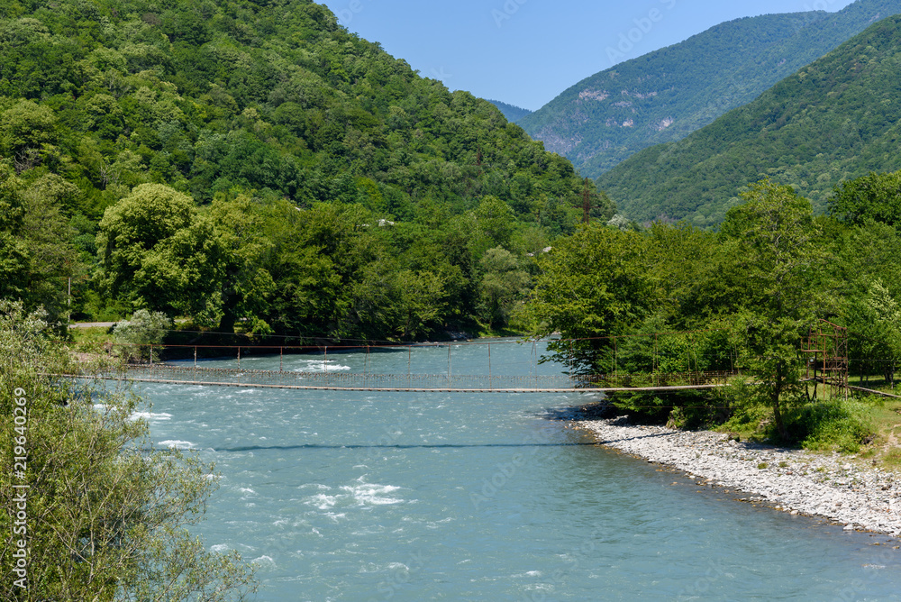 Suspension bridge over the mountain river in the mountains of Abkhazia Georgia