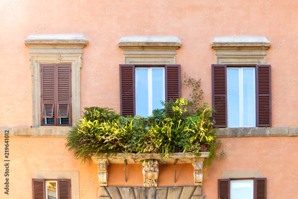 Bright colorful facade of old European building with Windows, balconies and flowers in Rome, Italy. Laconic minimalist concept.
