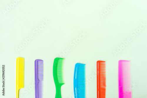 Many different multi-colored plastic hair comb crest brushes isolated on light green pastel background. Mininmalistic feminine hairdresser stylist concept. Flat lay  top view  copy space