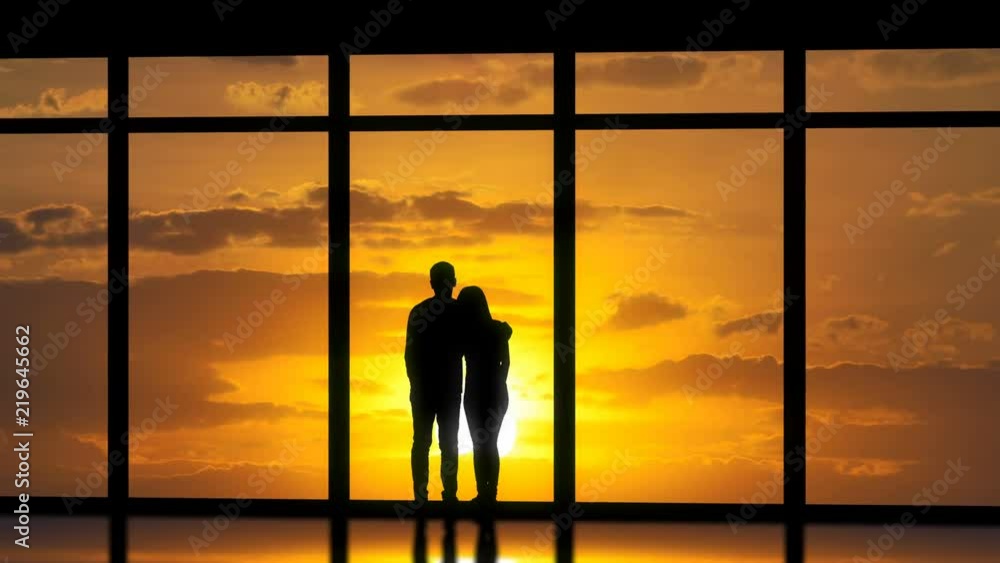 The couple standing near windows on the sunset background. time lapse The couple standing near windows on the sunset background. time lapse