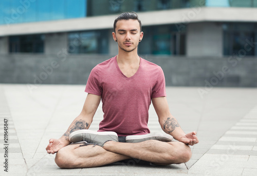 Handsome man practicing yoga in lotus pose outdoors © Prostock-studio