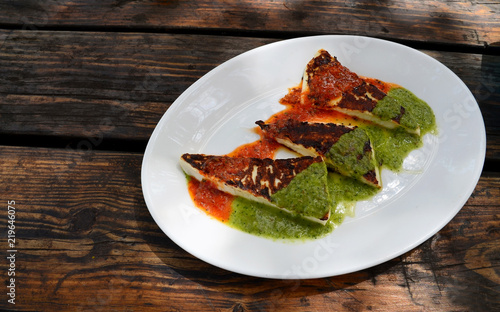 Grilled cheese with canarian sauces mojo rojo and mojo verde on a white plate.Traditional tapas on Tenerife,Canary Islands,
Spain.Selective focus.