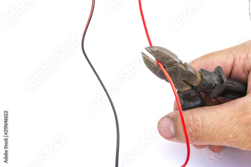 Hand cutting electric wire with wire cutters.