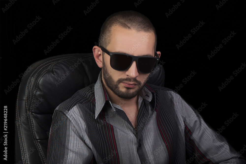 Obraz premium Portrait of serious handsome men in sunglasses over black bacground.