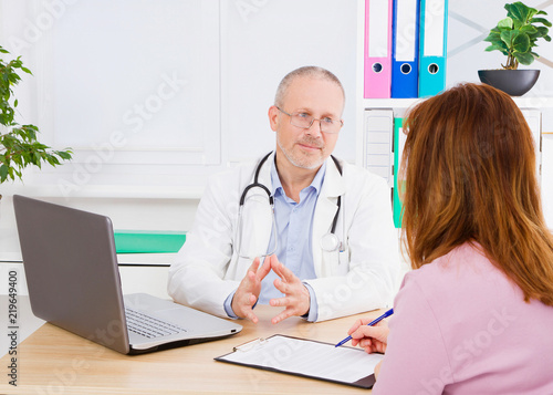 Doctor is talking with woman patient and sitting in medical office.Man in white uniform. Medical insurance. Copy space. Quality medicine concept.