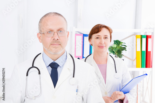 doctor posing in office with medical staff  he is wearing a stethoscope. Quality medicine concept. Man in white uniform. Medical insurance. Selective focus. Copy space