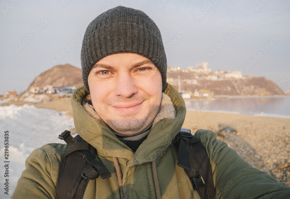 Young man makes selfie at frozen sea.