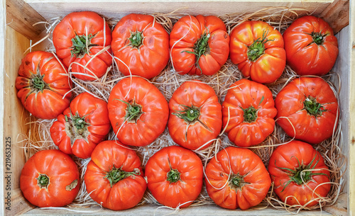 red tomatoes in box on a wooden background