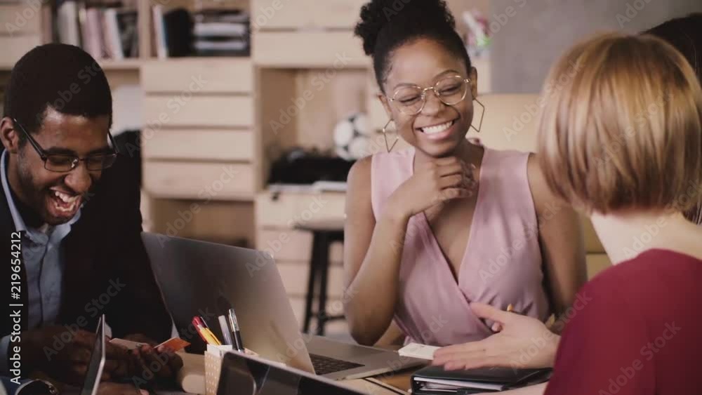 Cheerful African American female manager brainstorming with happy multiethnic colleagues in modern loft healthy office. Cheerful African American female manager brainstorming with happy multiethnic colleagues in modern loft healthy office.