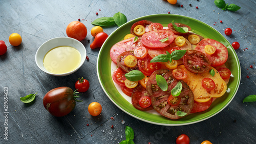 Colorful Tomato Salad with heirloom, pear shaped, beef heart, tigerella, brandywine, cherry, black tomatoes in a green plate. healthy food