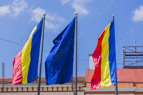 Romanian and EU flags waving on background of historic building facade