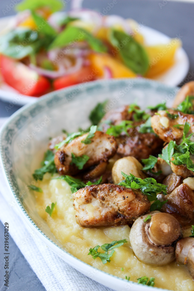 mashed potatoes with fried mushrooms and chicken on a side dish with tomatoes. mashed potatoes with fried mushrooms and chicken on a side dish with tomatoes.