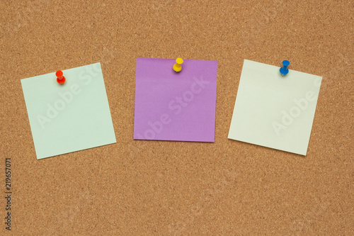 Three colorful sticky notes with pushpins and blank space, isolated on cork background, school concept