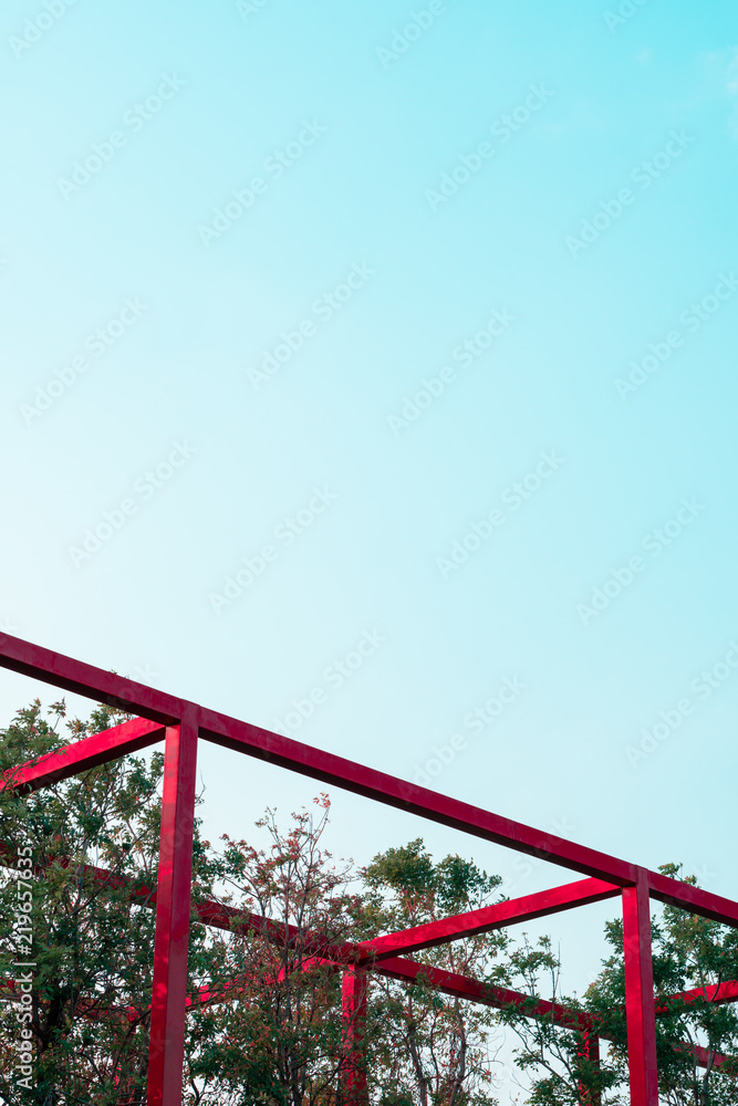 Abstract minimal red metal fixture architecture in tree park, Art geomatric shape construction in  outdoor design with blue sky