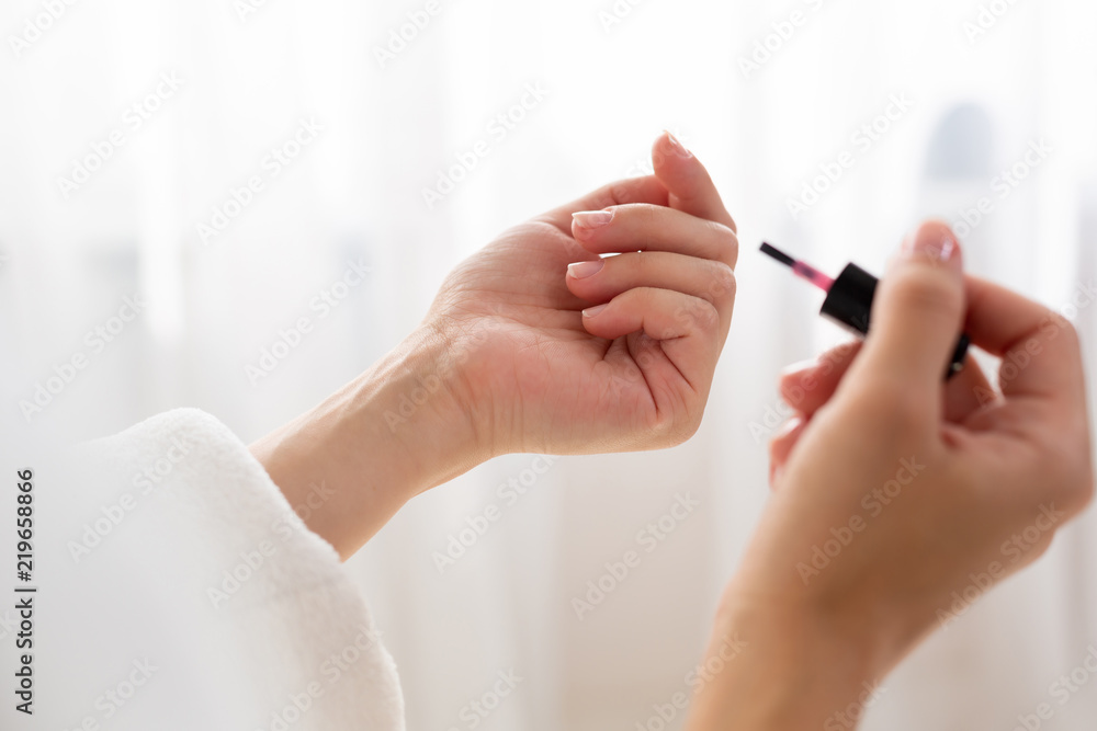 Close up of a shapely woman painted her nails in the morning, while sitting on the bed being dressed in a dressing-gown. Close up of a shapely woman painted her nails in the morning, while sitting on the bed being dressed in a dressing-gown.