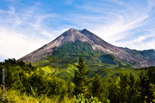 Scenic cone volcano with azure blue sky and clouds and green rainforest on Java island, Indonesia