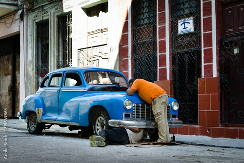 Two old men repairing old vintage american car on Havana streets, Cuba
