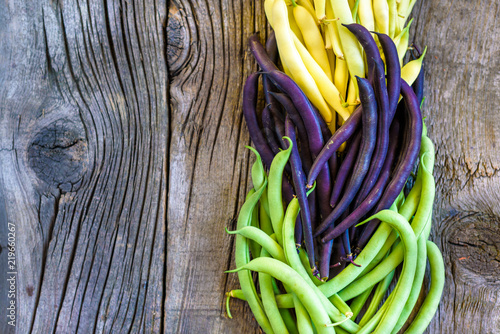 Collection of green, yellow and purple bush beans, opened green peas on wooden background photo