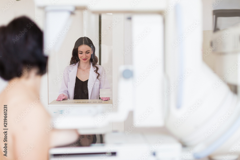 The young cheerful breast specialist carrying up the ultrasound examination of the breast of a patient in her office The young cheerful breast specialist carrying up the ultrasound examination of the breast of a patient in her office