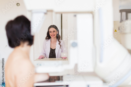 The young laughing breast specialist carrying up the ultrasound examination of the breast of a patient in her office