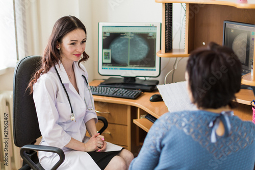 The young smiling breast specialist talking with the patient in her office