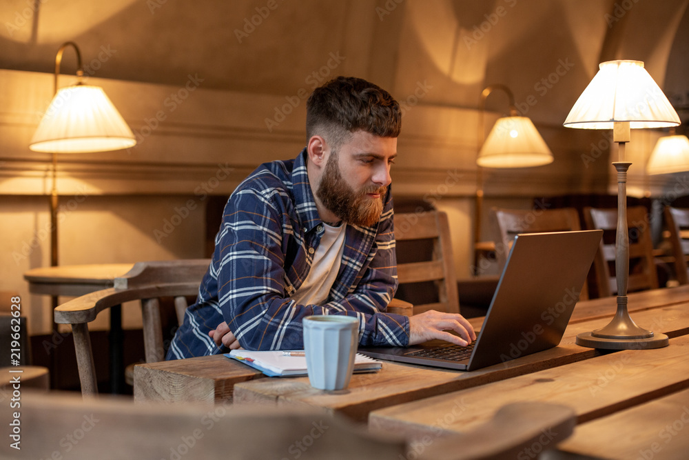 Young professional surfing the Internet on his laptop in a cafe Young professional surfing the Internet on his laptop in a cafe