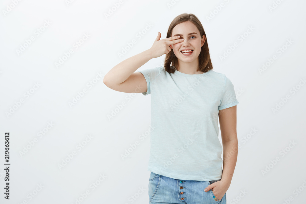 Reading words with one eye in optician store, picking new glasses. Portrait of joyful friendly-looking charming woman with short brown hair holding fingers on sight pointing right and smiling joyfully Reading words with one eye in optician store, picking new glasses. Portrait of joyful friendly-looking charming woman with short brown hair holding fingers on sight pointing right and smiling joyfully