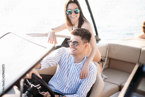 Wealthy succsessful businessman rent a speed luxury motor boat to take a drive with his new passion- young pretty girl with good slim body dressed in bikini. photo