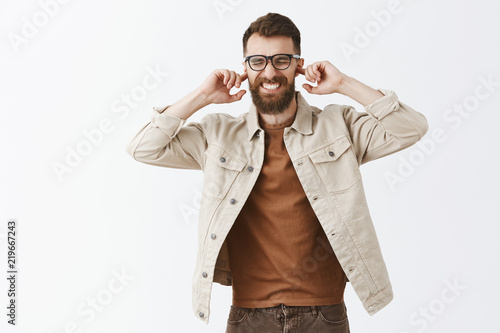 Portrait of intense disspleased mature european guy feeling discomfort covering ears with index fingers to protect hearing from loud disturing noise or band clenching teeth and closing eyes photo