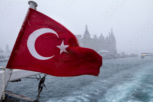  Turkish flag on a ship during a snowstorm, a Europe-Asia ferryboat can be seen in the background, as well as the Haydarpasa train station photo