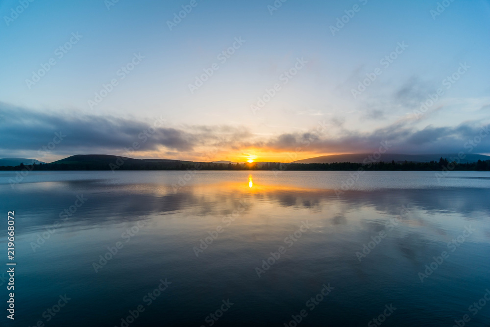 View of the sun setting over a lake in the Scottish Highlands.