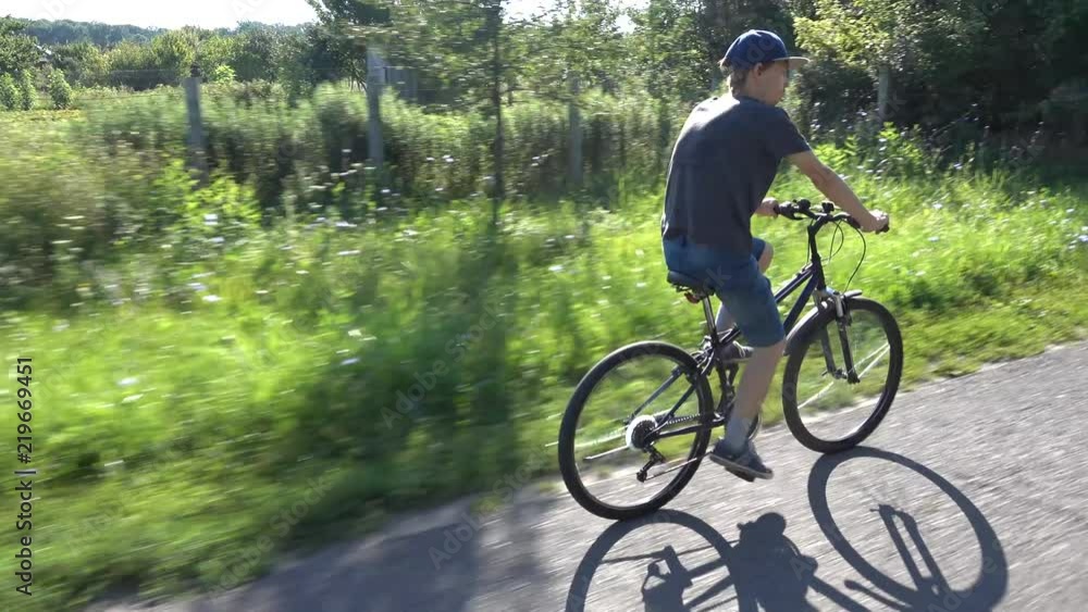 Handsome teenager boy riding bike on summer road Handsome teenager boy riding bike on summer road