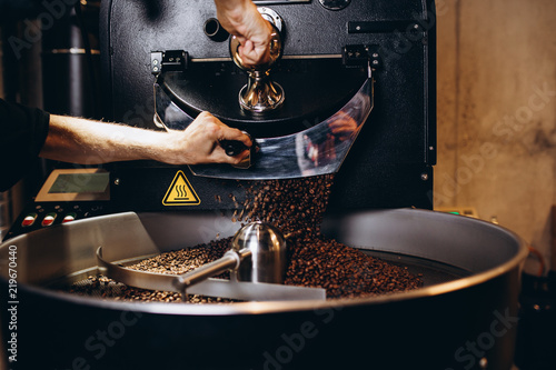 Freshly roasted coffee beans pouring from a large coffee roaster into the cooling cylinder.