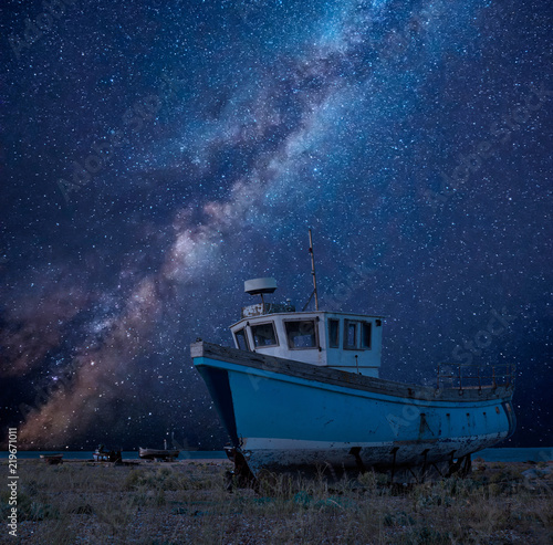 Vibrant Milky Way composite image over landscape of Abandoned fishing boat on shingle beach © veneratio