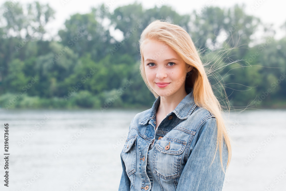 Beautiful young blonde woman in blue jeans with smile looking at camera on nature Beautiful young blonde woman in blue jeans with smile looking at camera on nature