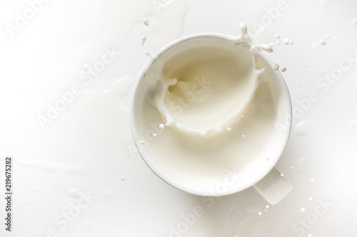 top view of milk splash out of glass on white background