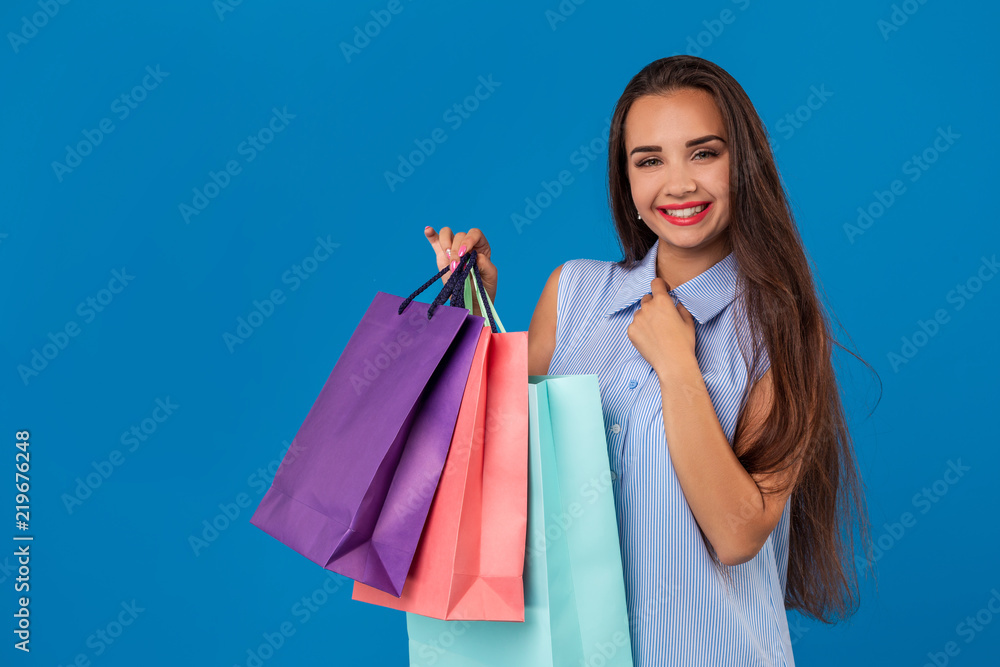 Beautiful young woman with colorful shopping bags on the wonderful blue background
