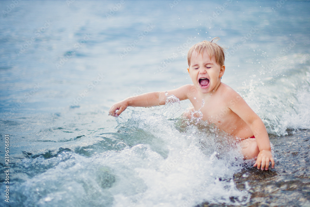 Happy boy playing at shallow water wave Happy boy playing at shallow water wave