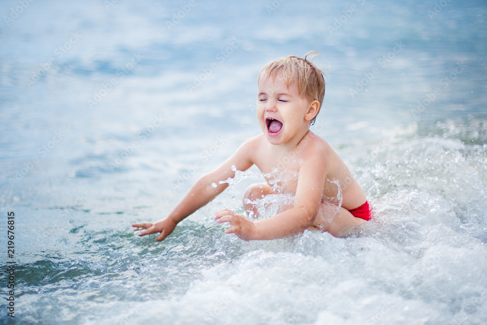Happy boy playing at shallow water wave