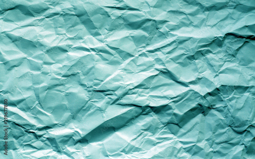 Obraz premium Crumpled sheet of paper with blur effect in cyan tone.