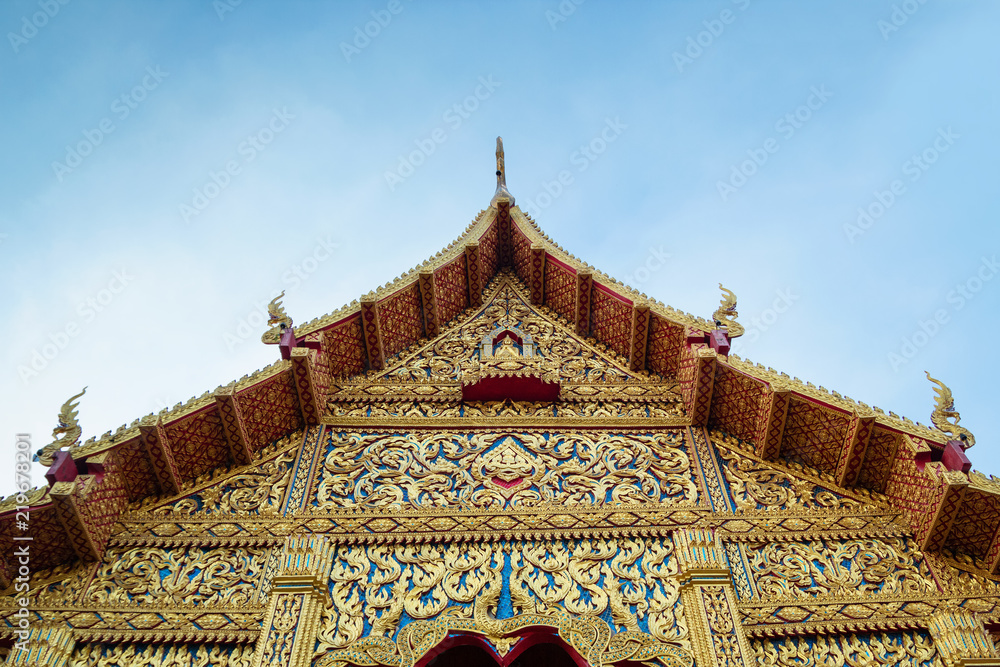 View on a traditional Buddhist temple on a background of blue sky. Chiang Mai, Thailand.
