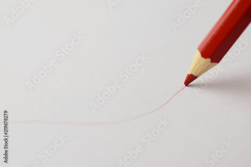 Red pencil drawing a red line on a white paper photo