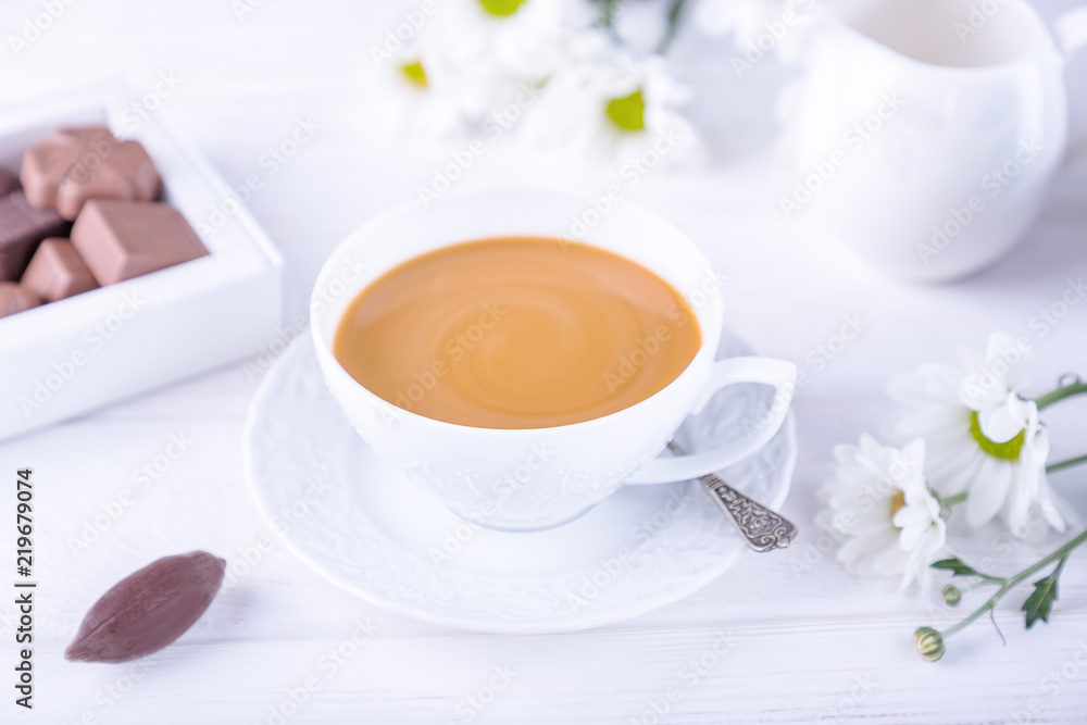 Coffee with milk, chocolate candies and chrysanthemums flowers on a white background Coffee with milk, chocolate candies and chrysanthemums flowers on a white background