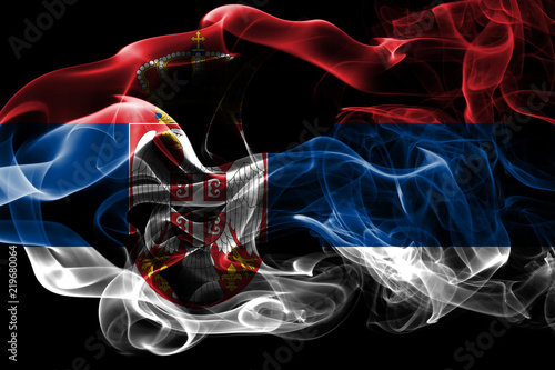 National flag of Serbia made from colored smoke isolated on black background. Abstract silky wave background.