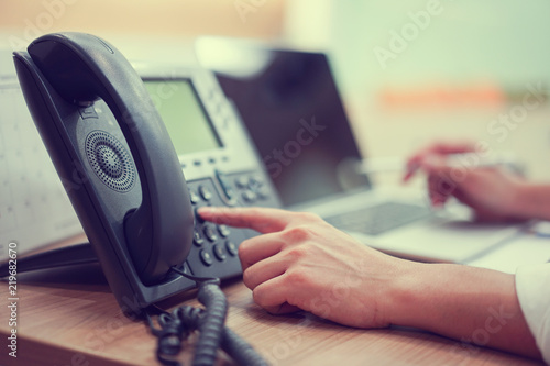 close up employee man hand pointing try to press button number on telephone office desk