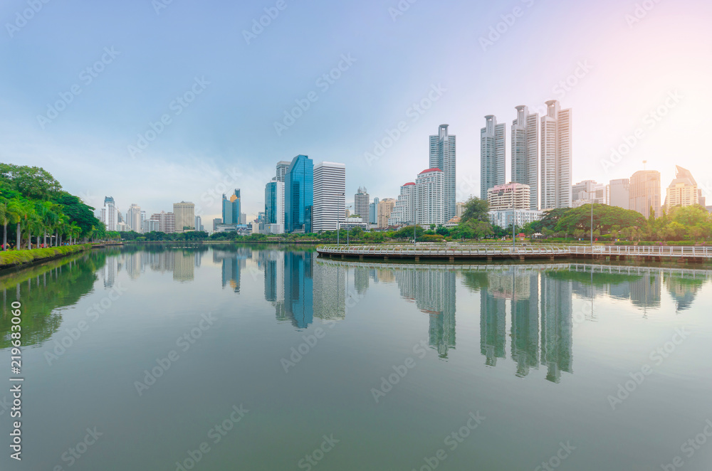 sunrise on morning city building skyline of skyscraper and green park with water reflection in downtown the cityscape landmark in Bangkok Thailand for business city and travel center.