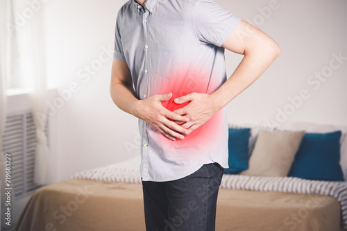 Stomach ache, man with abdominal pain suffering at home photo