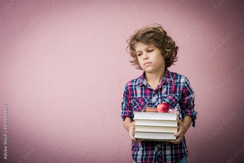 Little boy with stack of books frowning because he has to go back to school. Little boy with stack of books frowning because he has to go back to school.