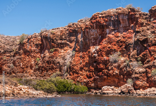 Exmouth, Western Australia - November 27, 2009: Yardie Creek Gorge in Cape Range National Park on North West Cape. Wider shot of Red and gray rock cliffs. Some green vegetation.